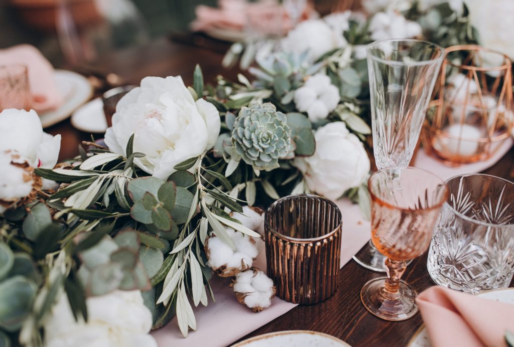 on wooden banquet table are glasses, plates, candles, table is d